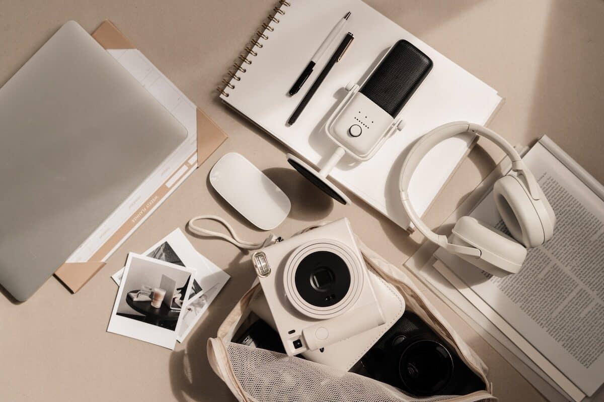 Multimedia devices and accessories including a camera, headphones, microphone, mouse, and laptop used for digital real estate marketing.