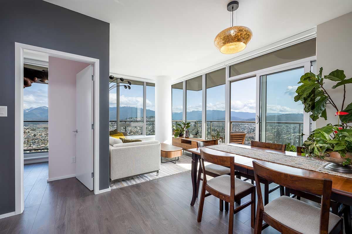 Bright, modern condo with mountain views, featuring a dining area, living room, and large floor-to-ceiling windows.