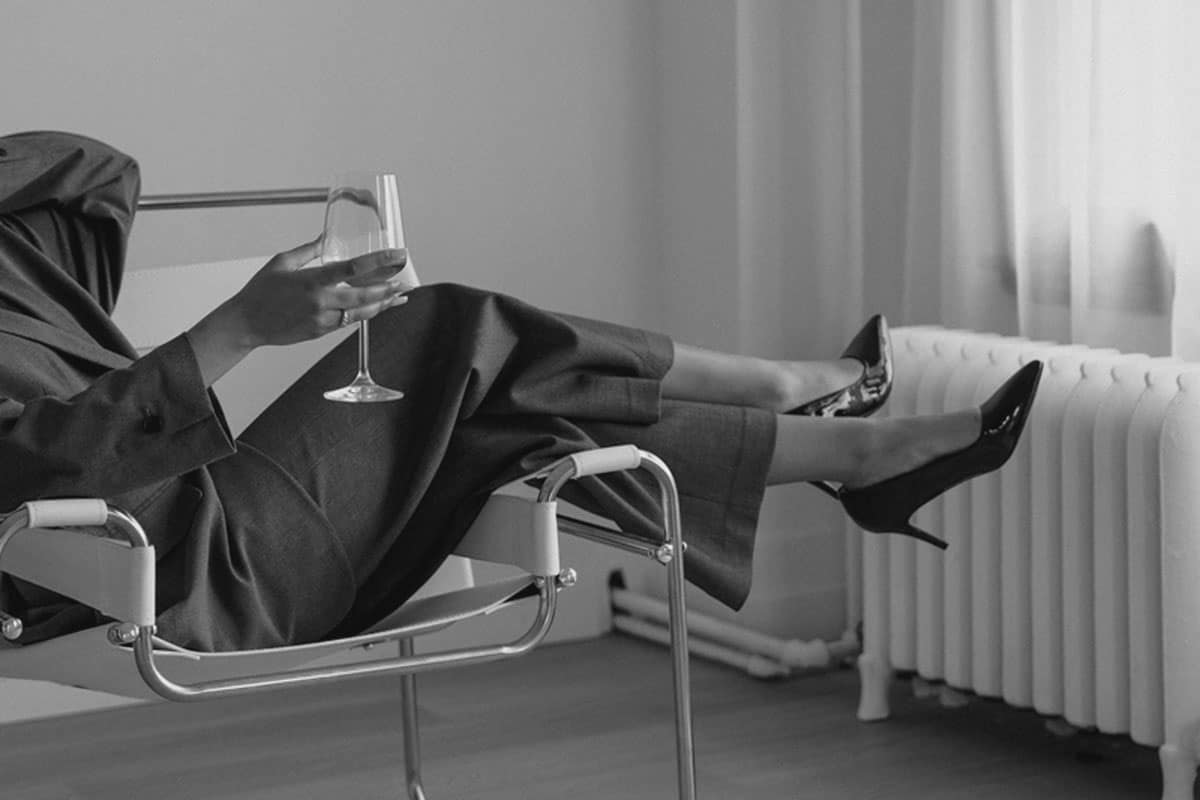 Professional relaxing in a modern chair with a wine glass, illustrating the ease of using our tenant placement service.