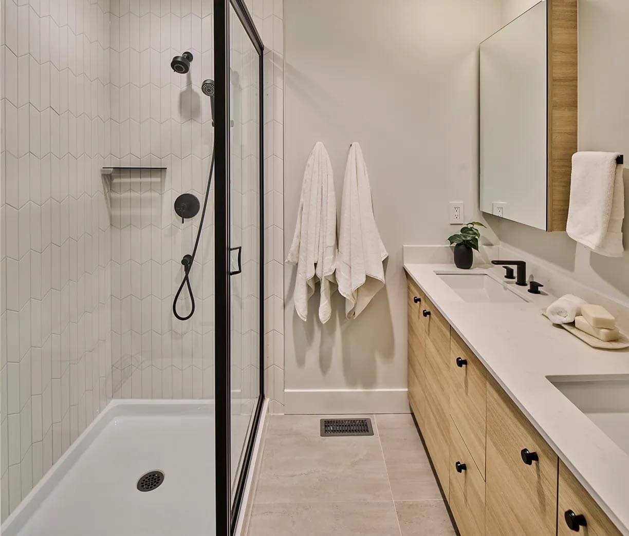 Walk-in shower at Addition Langley presale in Langley’s Willoughby with modern vertical tile pattern, black fixtures, and built-in niche by Redekop Ferrario Properties