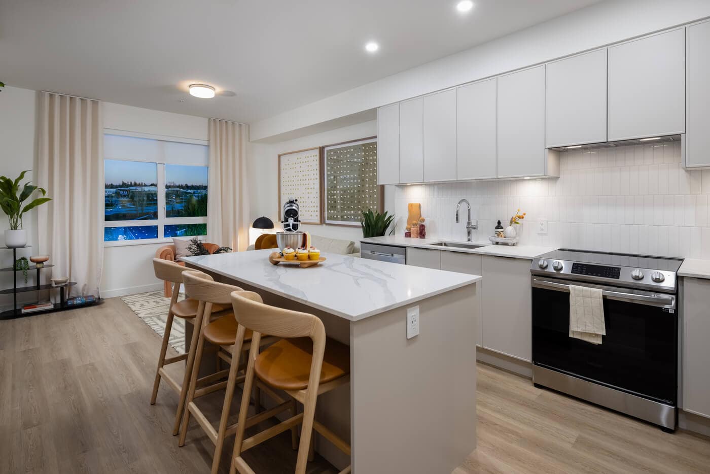 Open-concept condo interior at Jericho Park Langley by Essence Properties featuring kitchen island seating, living area, large windows, and modern finishes at 19925 78B Avenue.