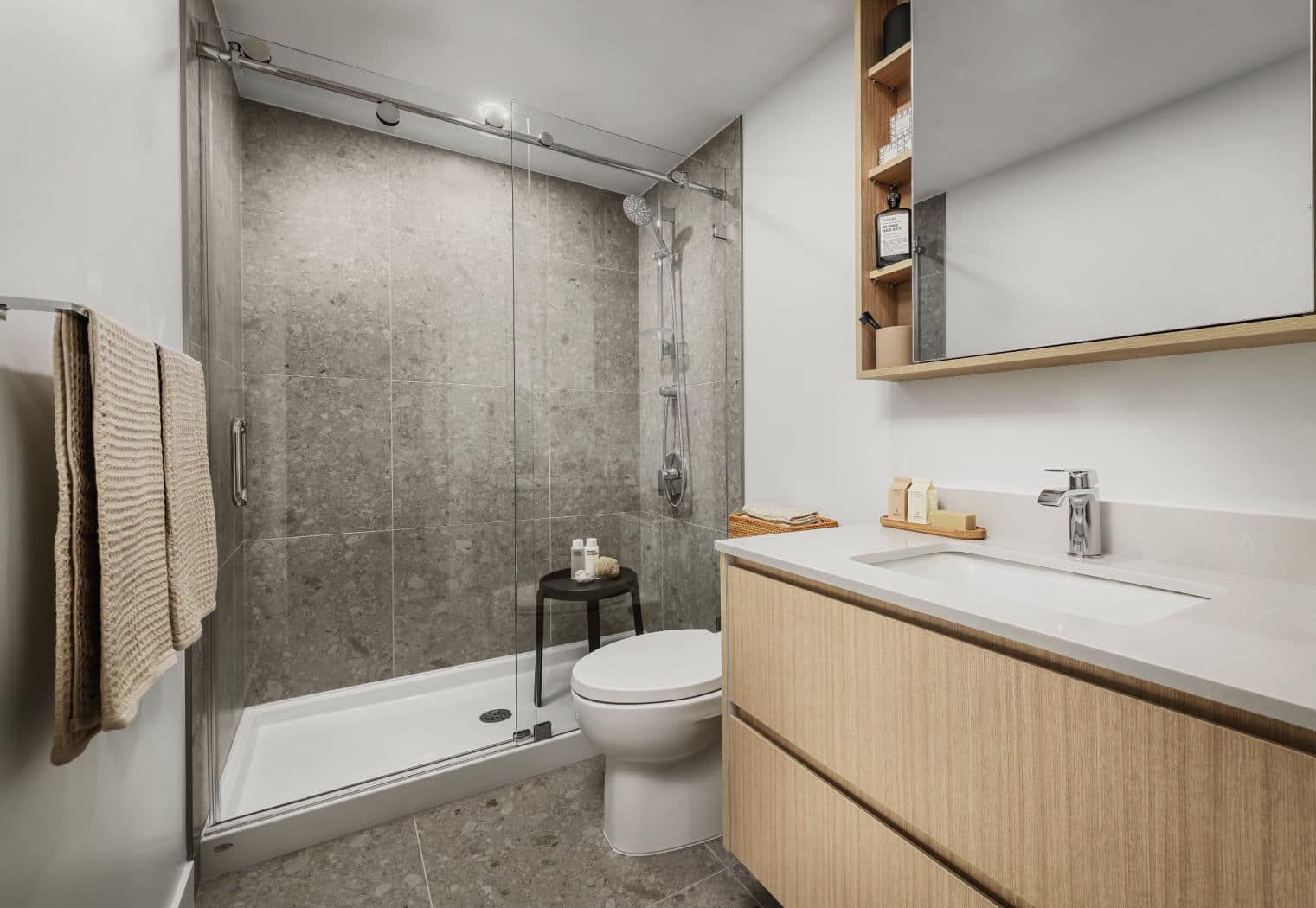 Modern bathroom at Gardena Coquitlam by Intracorp at 635 Gardena Drive, featuring a glass-enclosed shower, large format tile, wood vanity, integrated sink, and clean contemporary finishes in Burquitlam.