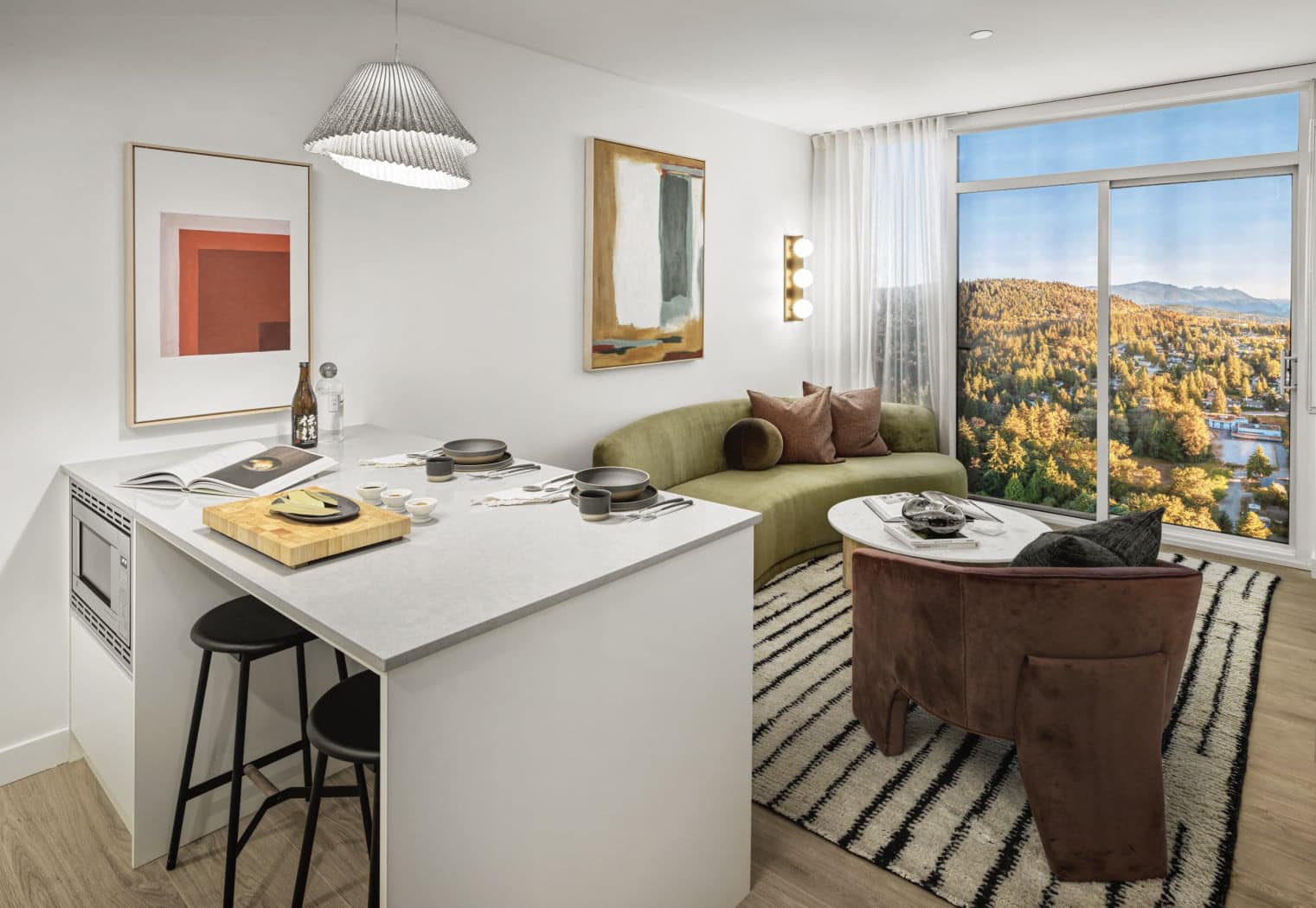 Combined kitchen and living space at Gardena Coquitlam by Intracorp located at 635 Gardena Drive in Burquitlam, showcasing modern finishes, island dining, comfortable seating, and large windows with scenic outdoor views.