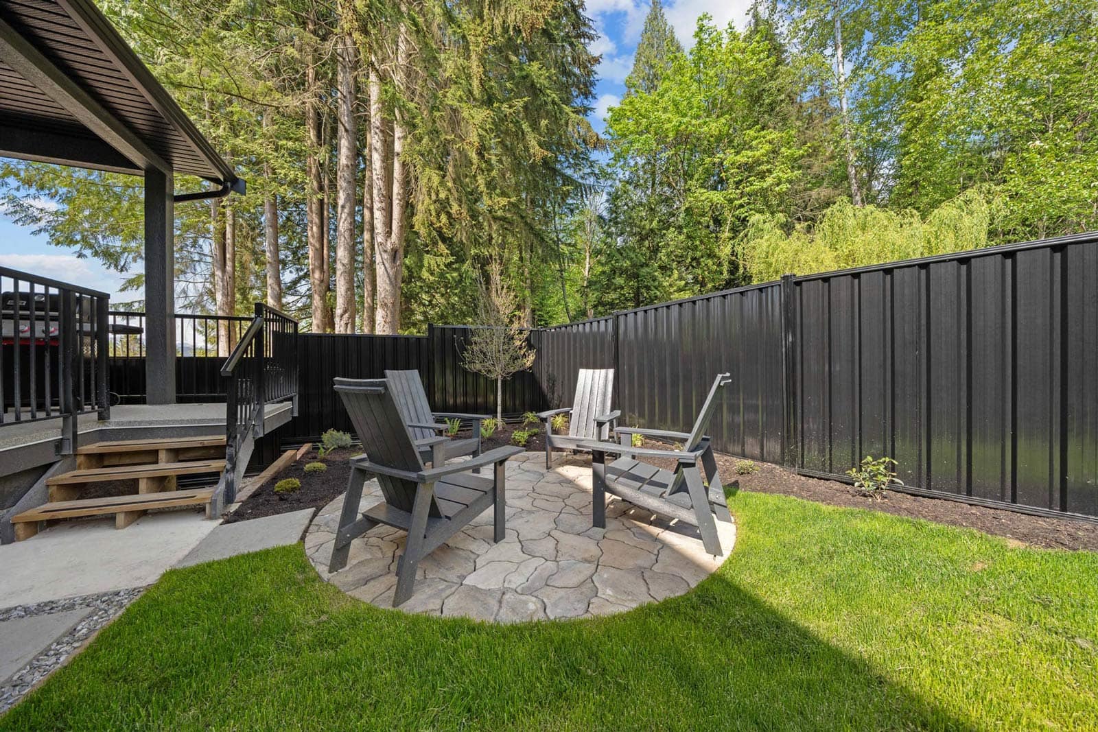 Private backyard patio at Haven Maple Ridge by Epic Homes at 11205 250B Street with seating area, lawn, and fenced yard backing onto greenery