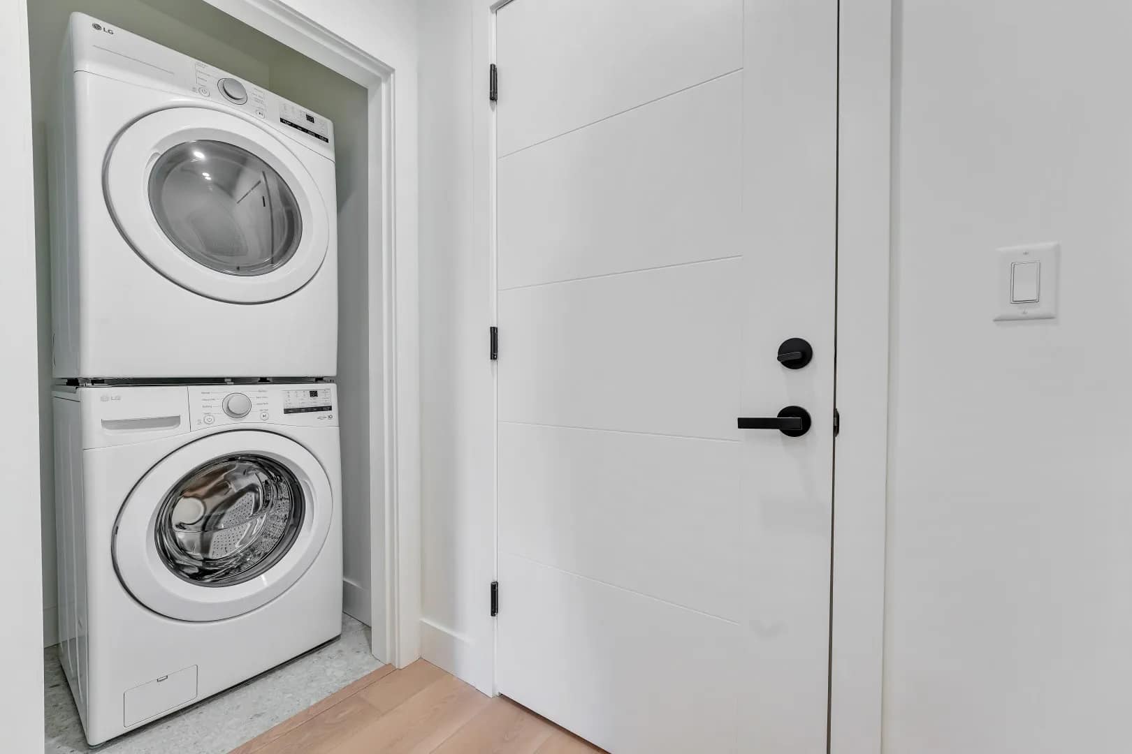 Stacked washer and dryer in Jethro Langley condo at 5362 204 Street, Langley City, with modern in-suite laundry by Whitetail Homes