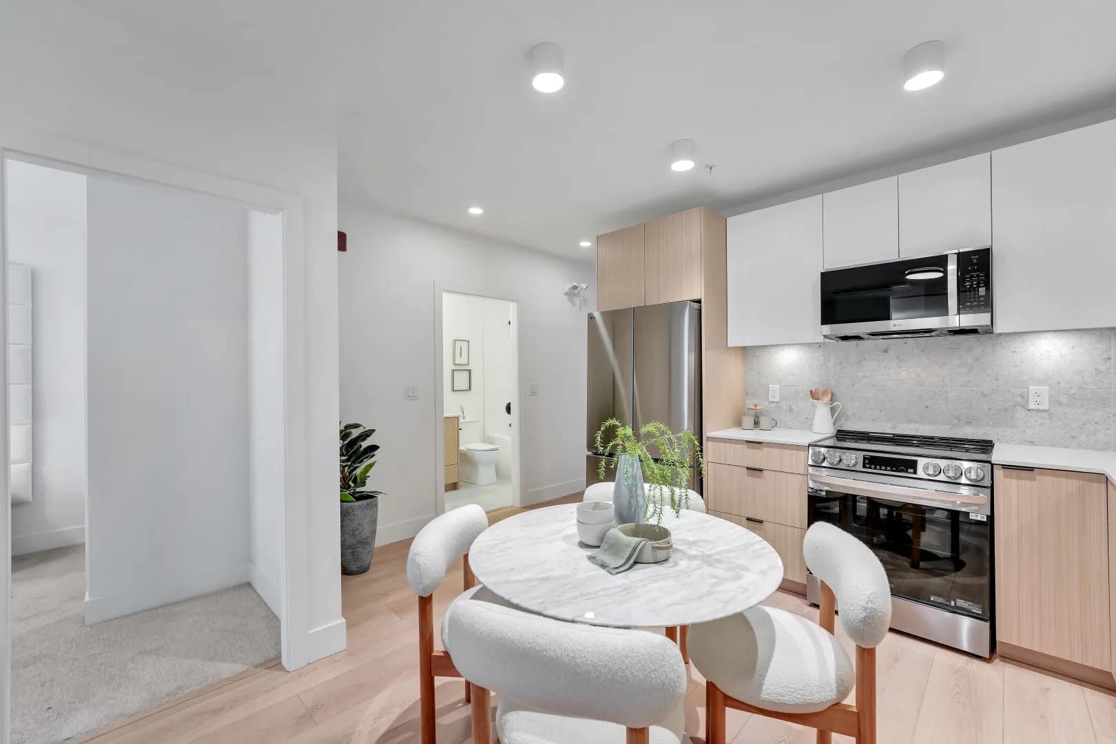 Kitchen and dining area at Jethro Langley in Langley City with round dining table, light wood cabinetry, stainless steel appliances, and modern open-plan design.