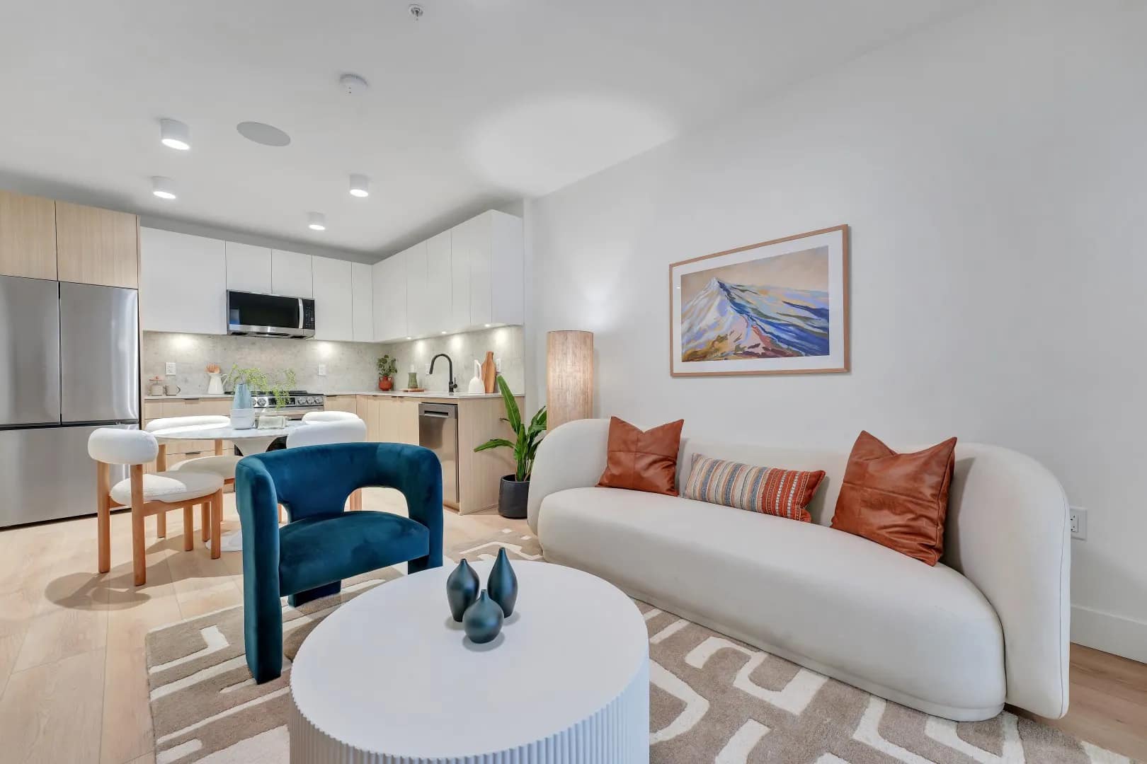 Open-concept living room and kitchen at Jethro Langley in Langley City, featuring modern cabinetry, stainless steel appliances, dining space, and contemporary furnishings by Whitetail Homes.