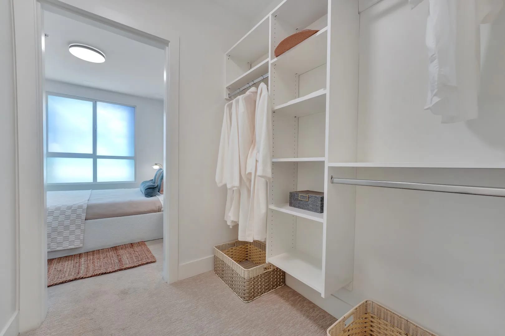 Walk-in closet at Jethro Langley Langley City with open shelving, hanging space, baskets, and direct connection to the primary bedroom.