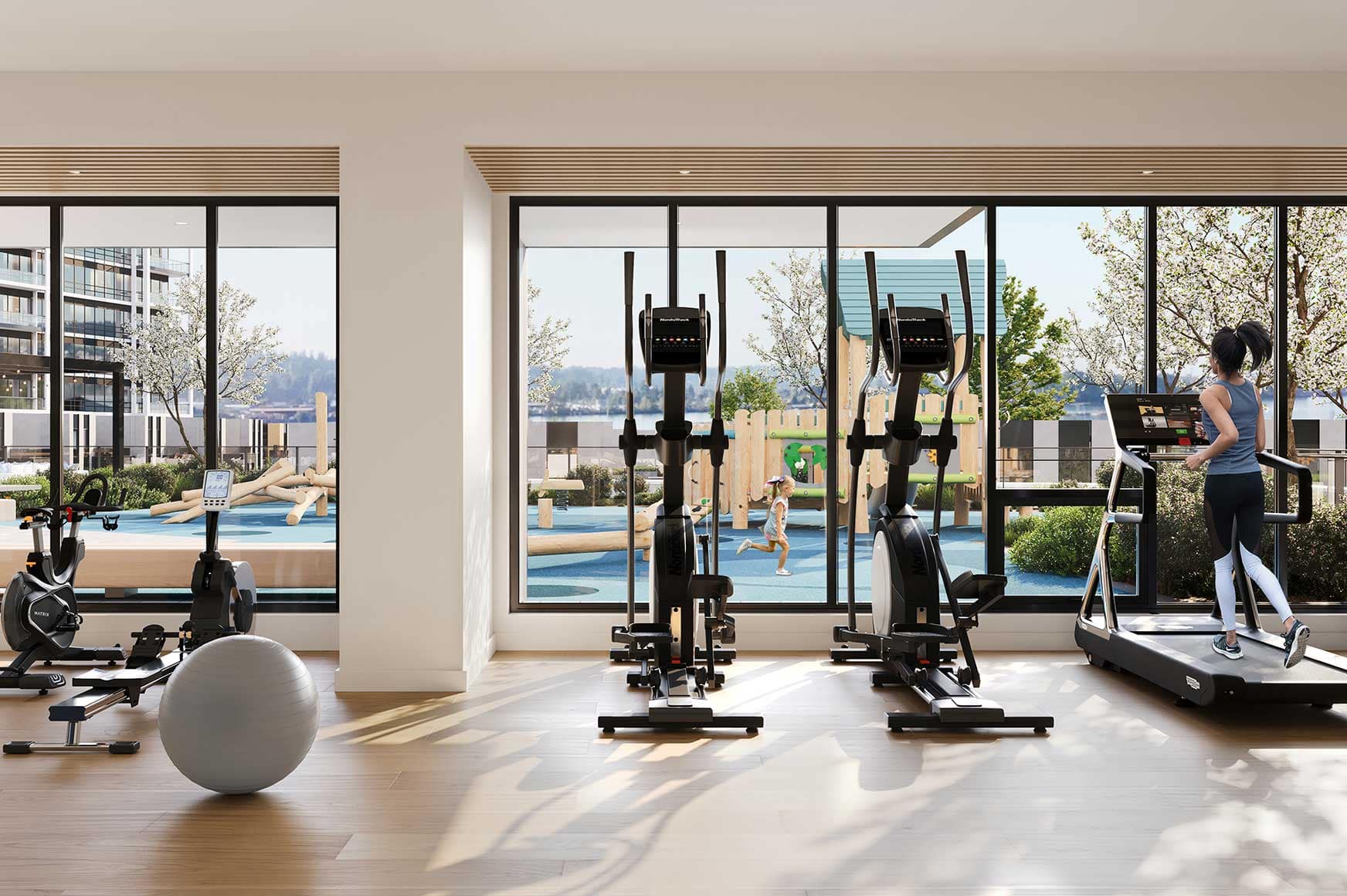 Fitness centre at Encore Coquitlam featuring cardio equipment, strength training space, large windows, and views overlooking outdoor amenities within the Fraser Mills community.