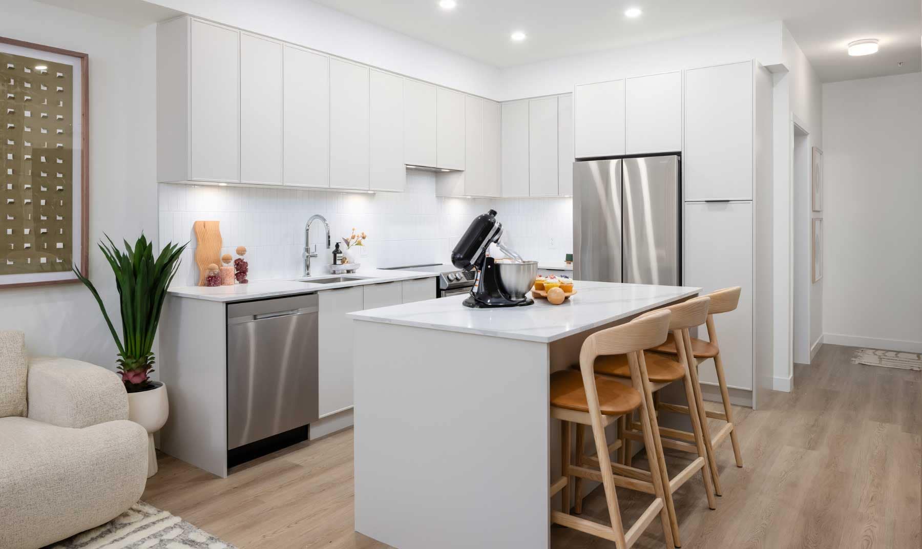 Modern condo kitchen interior at Jericho Park Langley by Essence Properties featuring white cabinetry, quartz countertops, stainless steel appliances, large island seating, and contemporary finishes at 19925 78B Avenue in Langley.