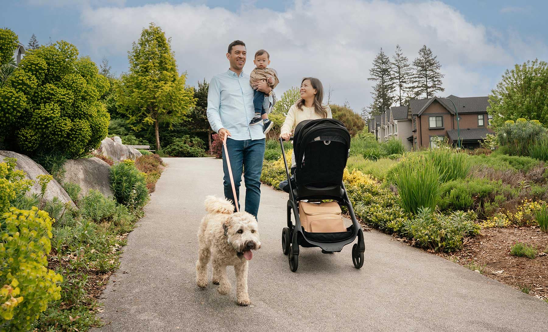 A family walking with a stroller, young child, and dog through a landscaped neighbourhood park near Beaumont Burke Mountain by Polygon at 3630 Harper Road in Coquitlam, showcasing the community's family-friendly environment, green spaces, and outdoor lifestyle.