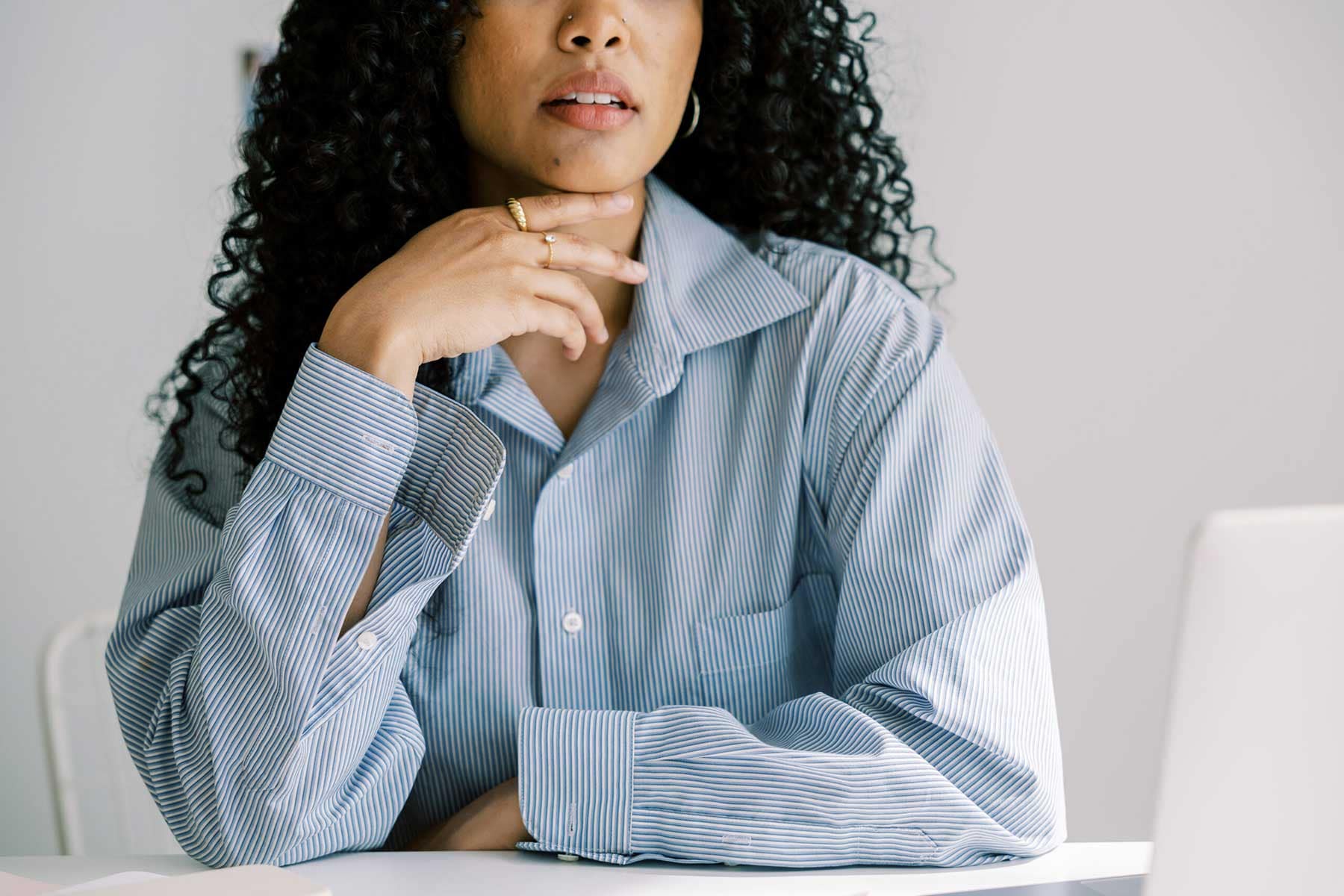 Woman sitting at a desk with a thoughtful expression, contemplating the current market value of her home.
