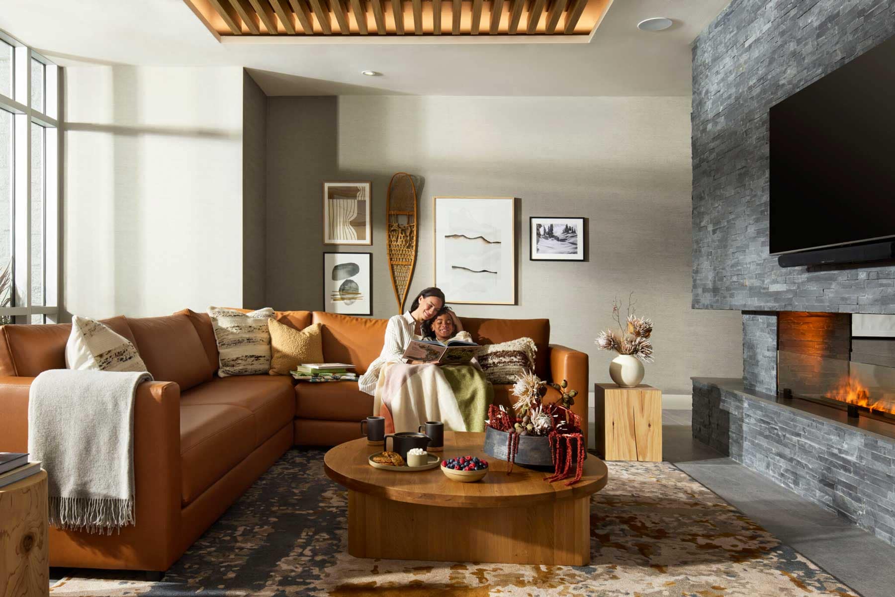 Cozy fireside residents lounge at Trailside at Lynn by Mosaic in North Vancouver featuring stone fireplace, contemporary seating, warm wood finishes, and community gathering space at 2380 Emery Court.