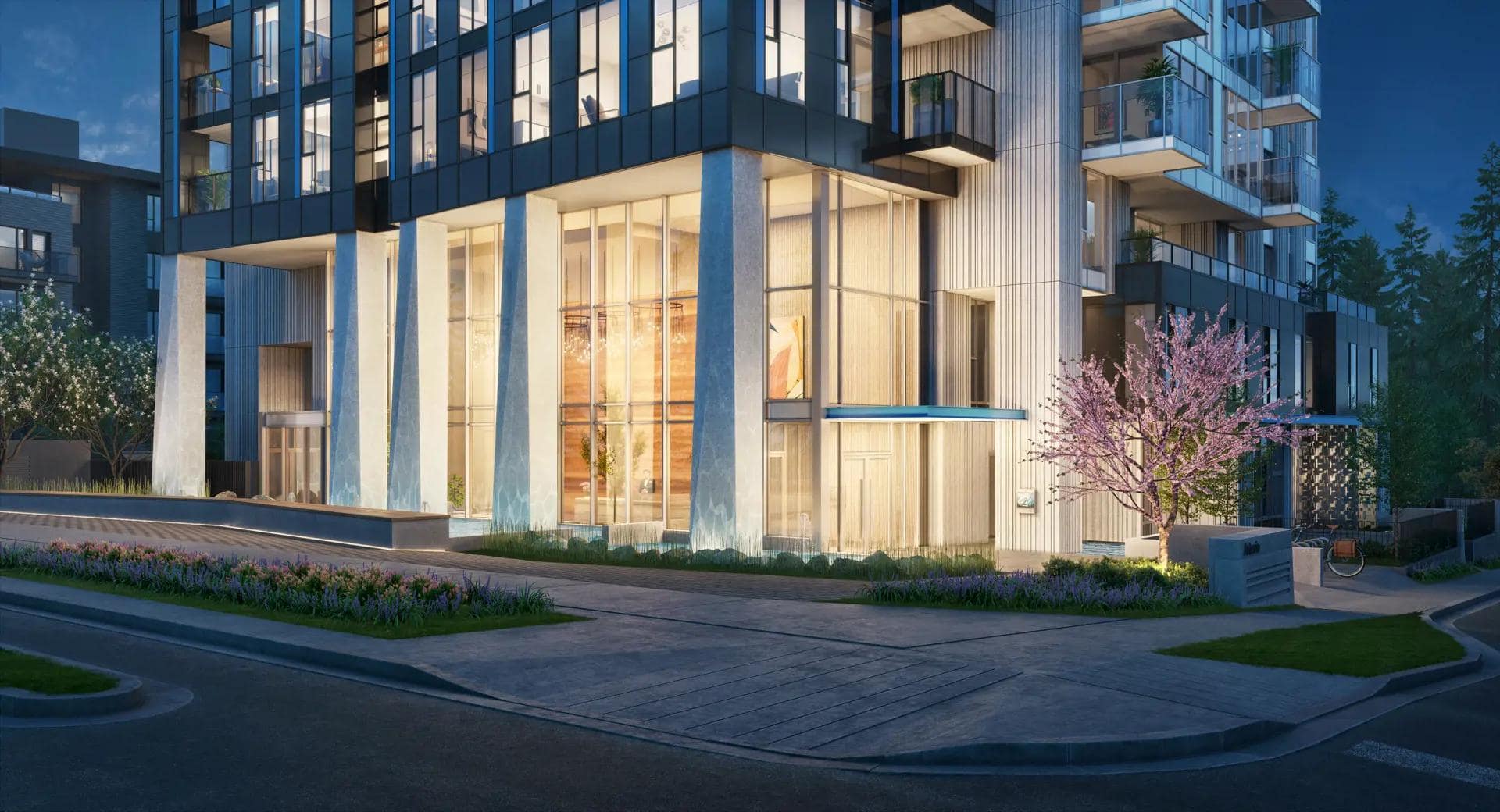 Illuminated Artesia Burnaby entrance at night with modern glass faรงade and landscaping.