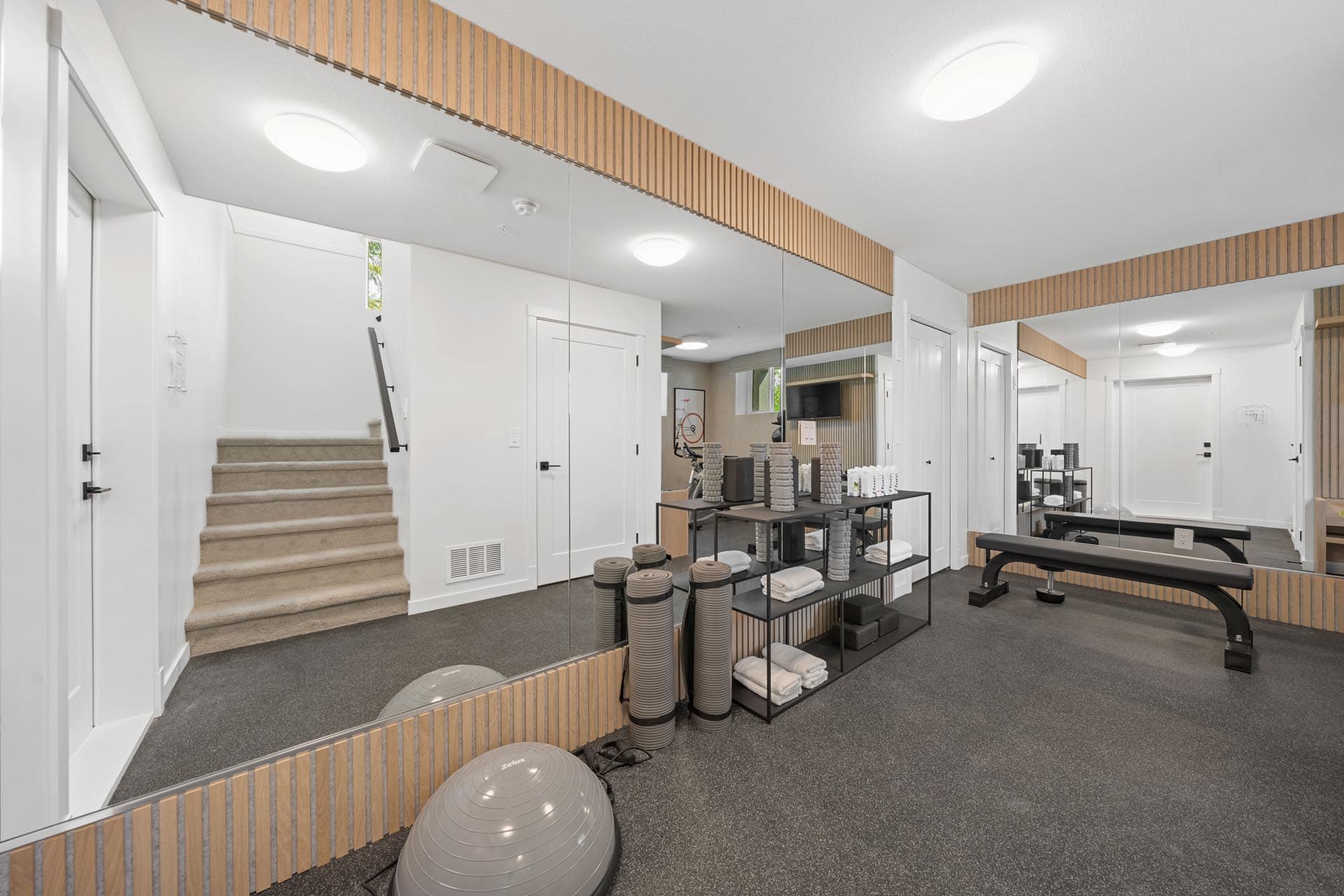 Private fitness room at Haven Maple Ridge by Epic Homes at 11205 250B Street featuring mirrors, workout equipment, and modern finishes