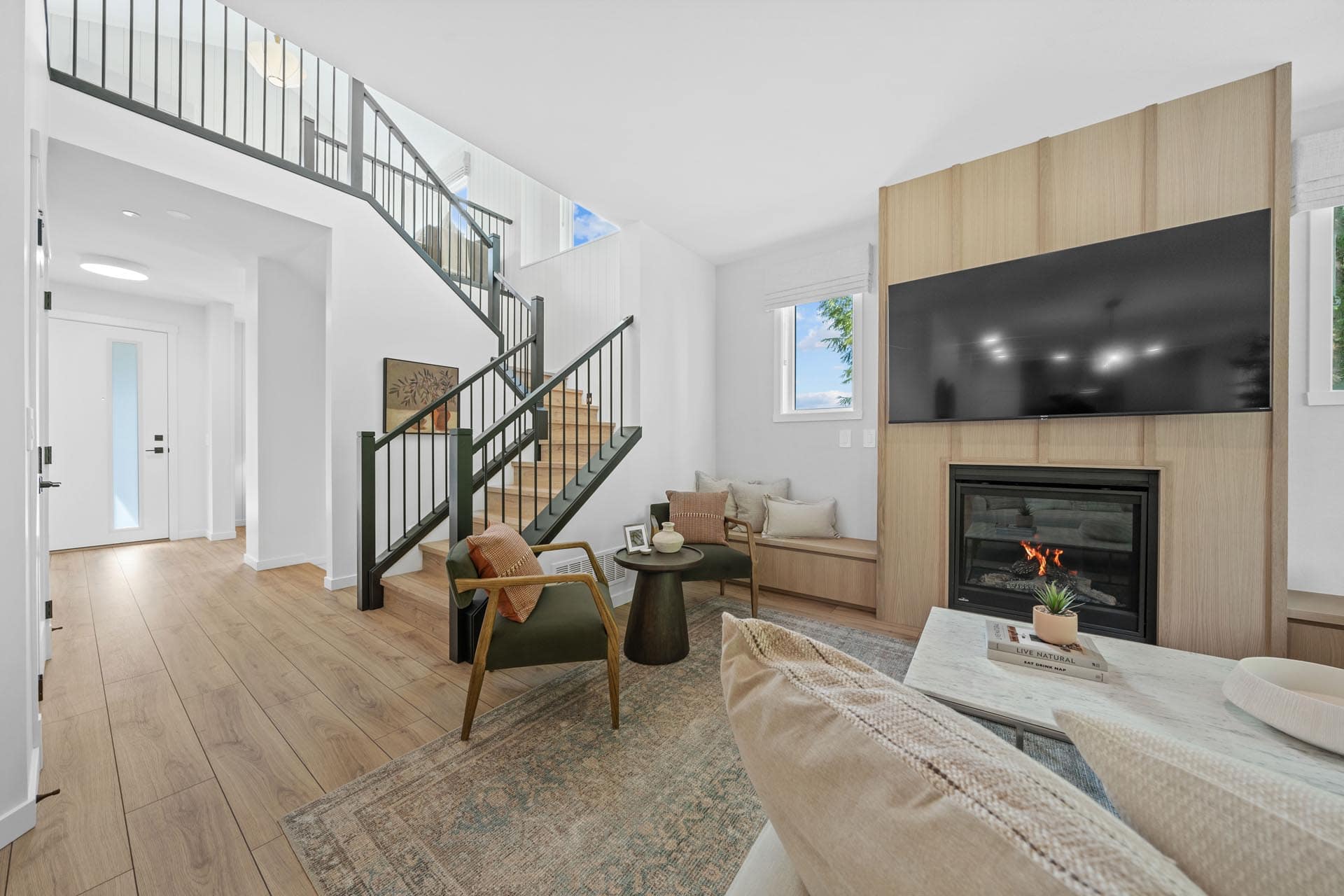 Open living area at Haven Maple Ridge by Epic Homes at 11205 250B Street with staircase, fireplace feature wall, and wood flooring