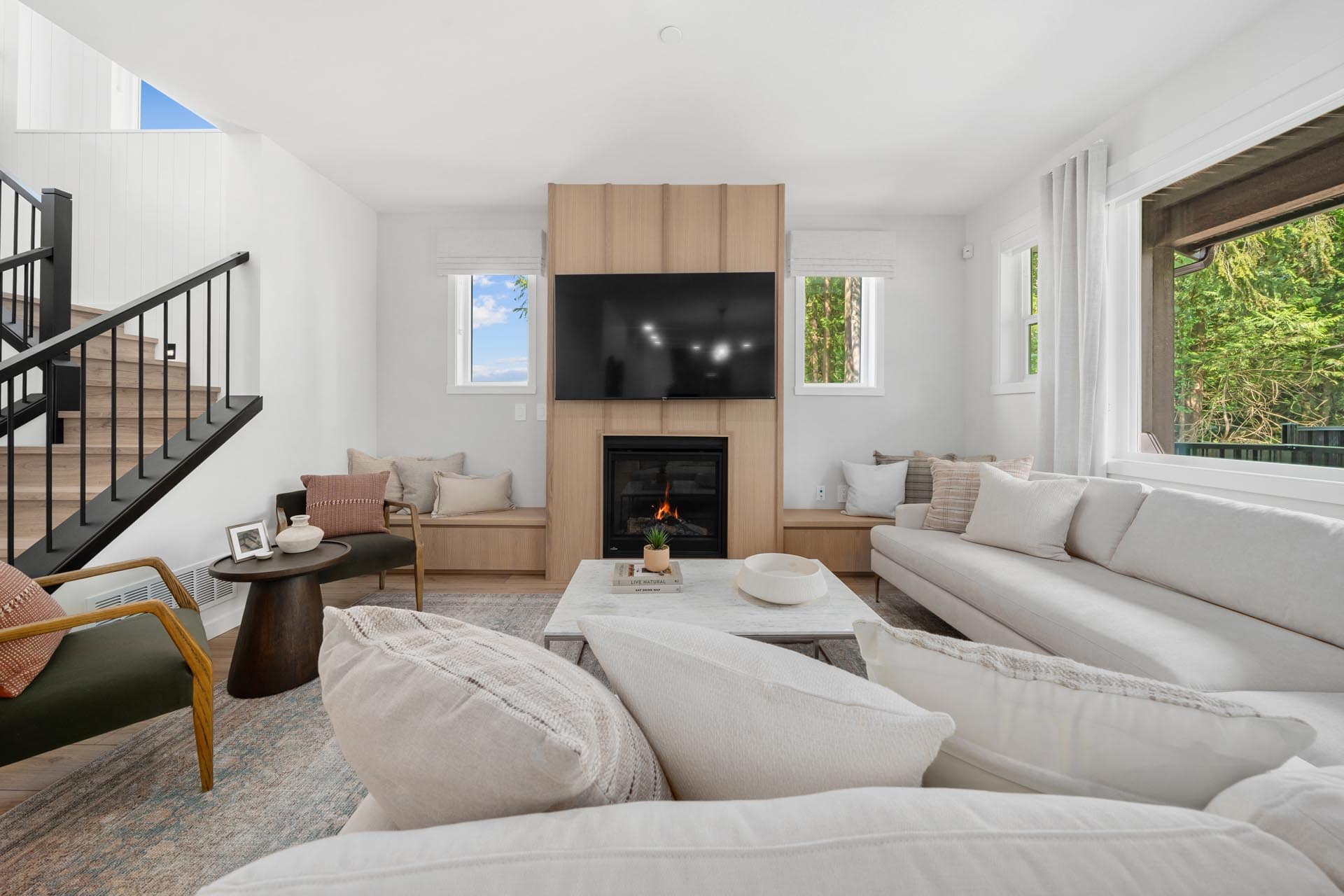 Bright living room at Haven Maple Ridge by Epic Homes at 11205 250B Street with fireplace, built-in seating, large windows, and neutral furnishings