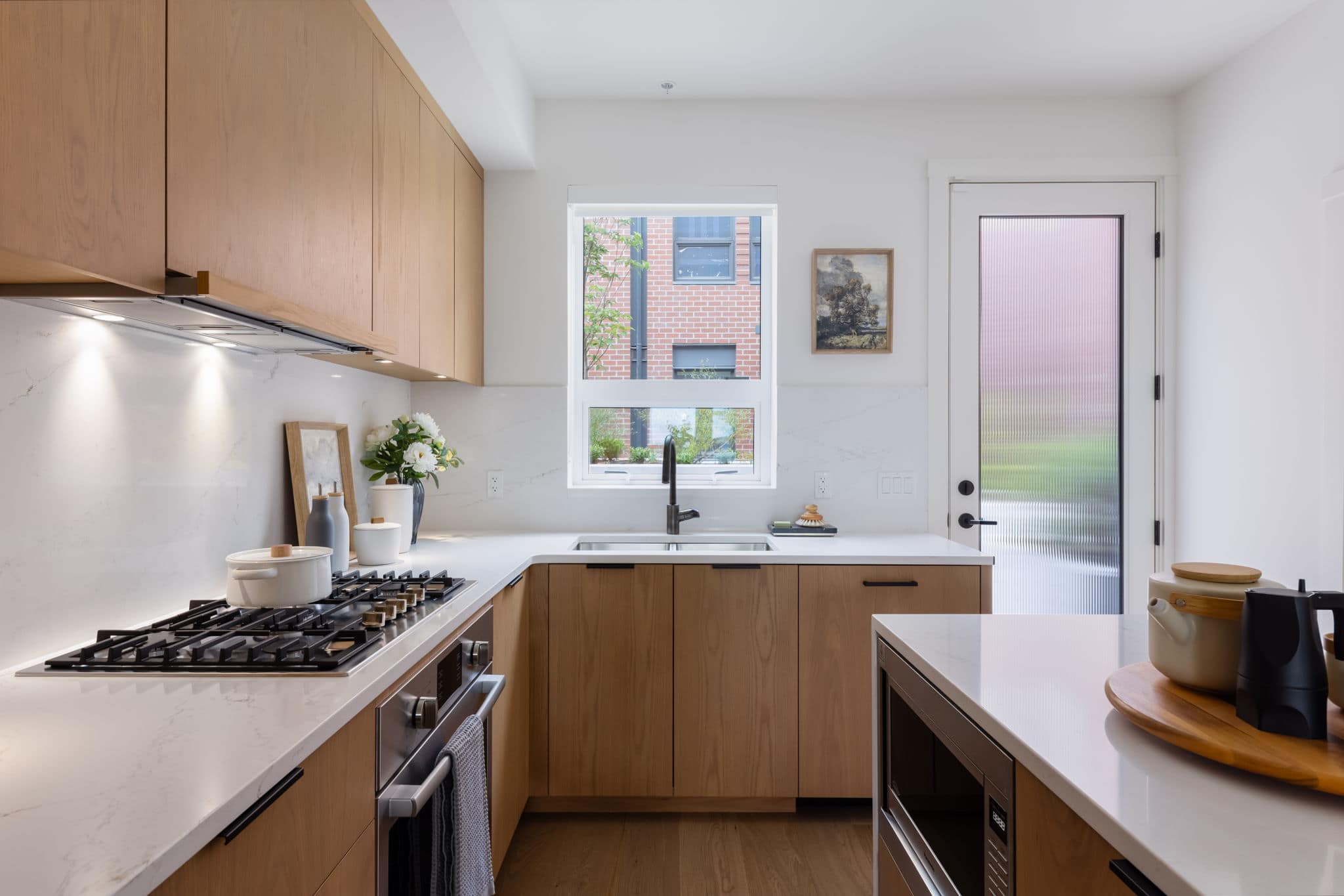 Bright contemporary kitchen inside York Vancouver townhomes by Listrator at 802 West 37th Avenue in Vancouver’s Cambie Corridor, featuring quartz countertops, integrated appliances, oak cabinetry, and natural light from oversized windows.