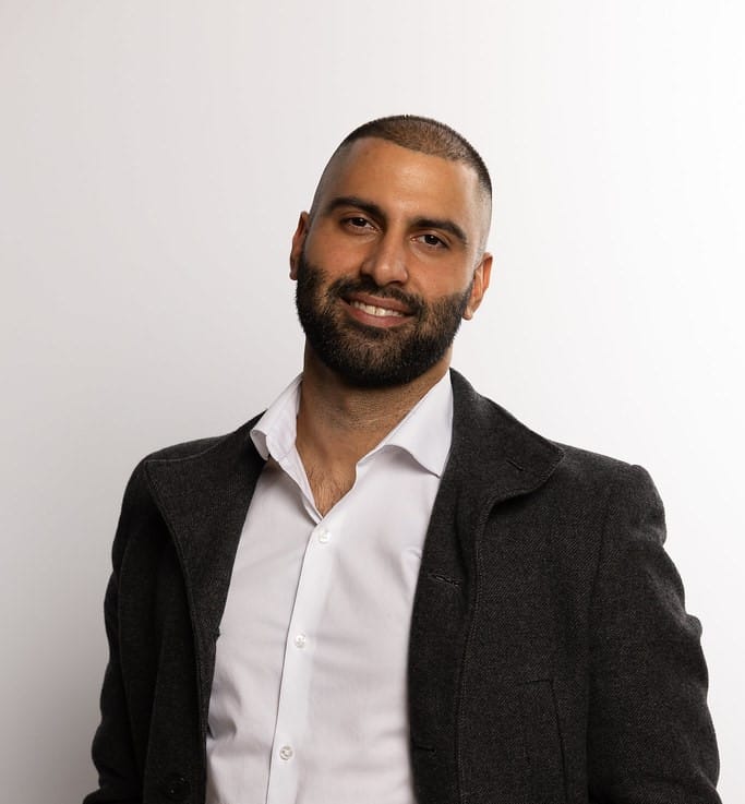 Punjabi mortgage broker Pav Gill from DLC A Better Way smiling in a professional portrait.