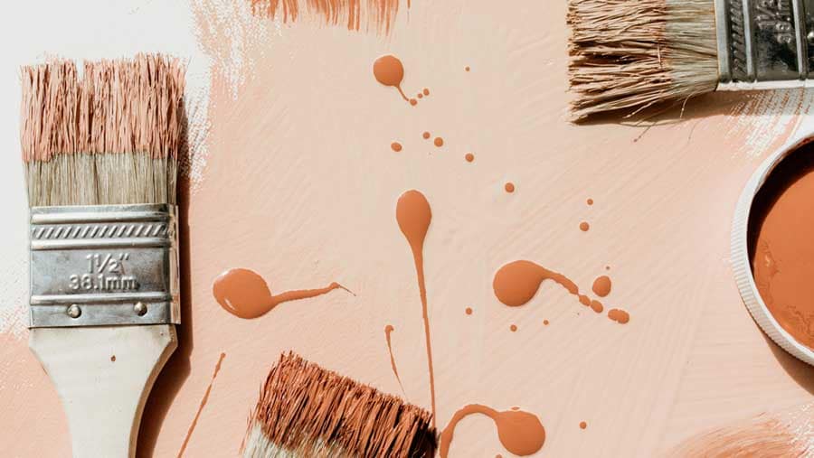 Paint brushes and warm neutral paint tones arranged on a work surface, used to represent cost-effective home improvements that matter most when selling in a slow real estate market, emphasizing simple cosmetic updates, buyer appeal, and strategic preparation for Metro Vancouver and Fraser Valley home sellers in 2026.