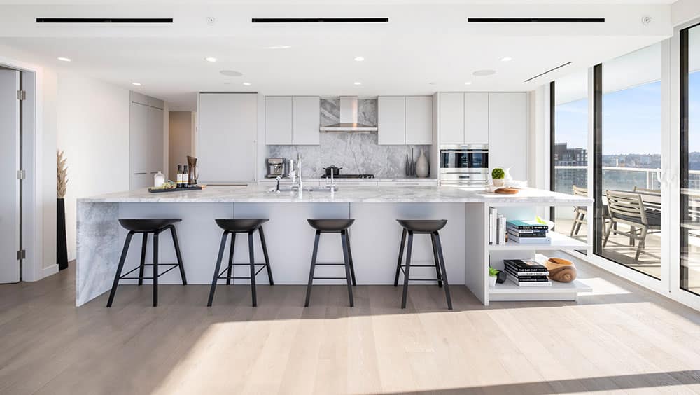 Contemporary kitchen at 1535 Howe Vancouver by Onni with marble waterfall island, integrated appliances, sleek cabinetry, and large windows overlooking Downtown Vancouver at 1335 Howe Street.