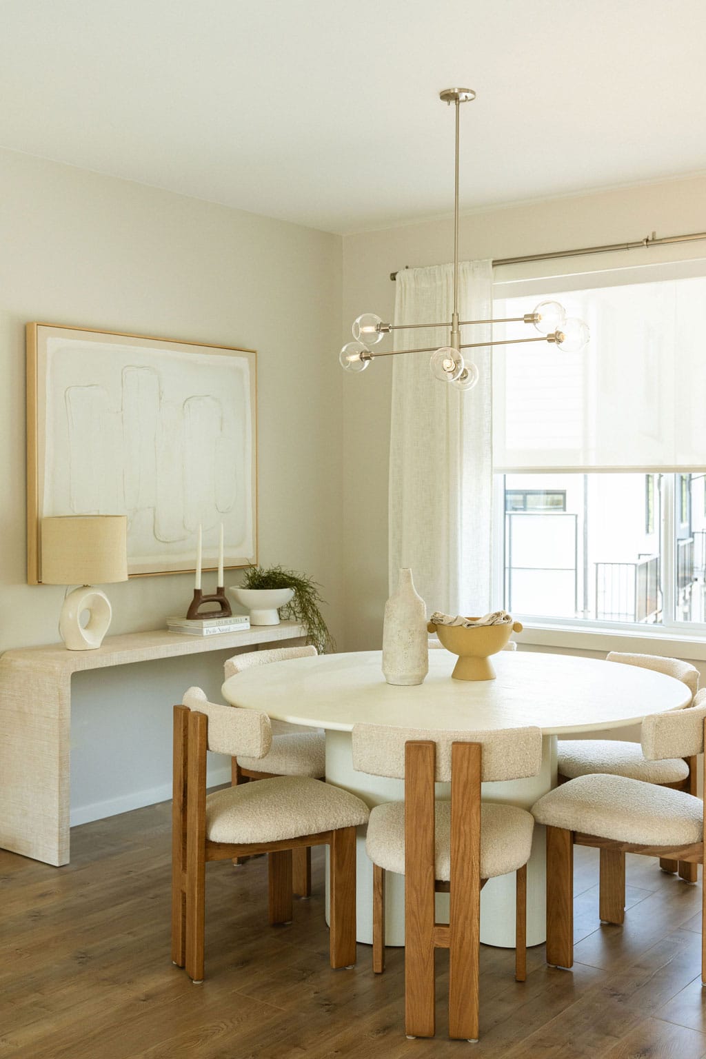 Dining room at Fox & Aikins South Surrey townhomes by Park Ridge Homes, 1871 165A Street, showcasing a round dining table with upholstered chairs, contemporary chandelier, wide plank flooring, large window, and neutral designer finishes.