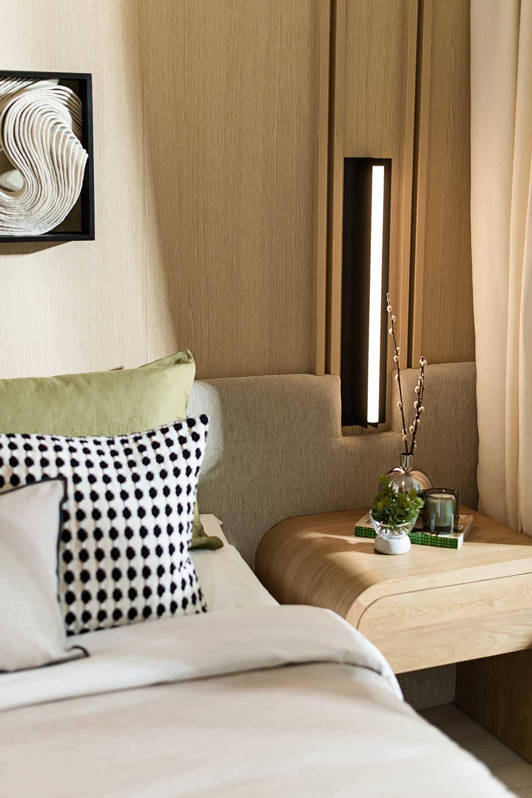Bedroom lighting feature at Jinju Coquitlam presale condos by Anthem Properties, 533 Cottonwood Avenue in Burquitlam, with built-in vertical light fixture, wood paneling, and styled bedside decor.