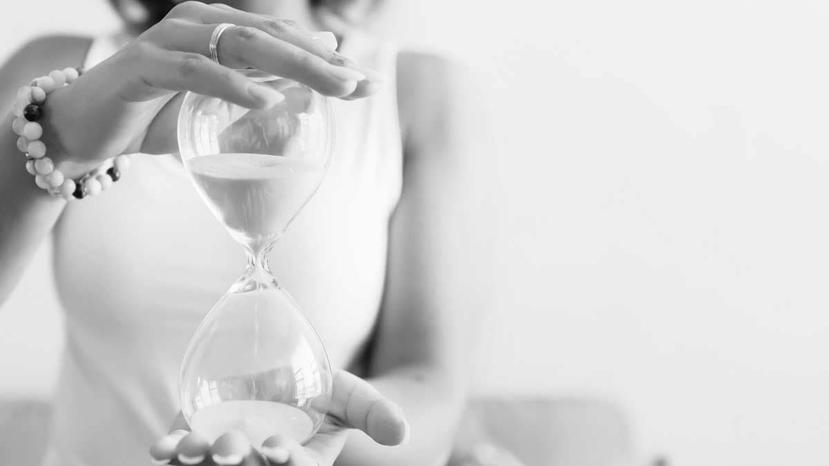 Woman holding an hourglass, representing time running out for BC home sellers with a property that isn't selling.