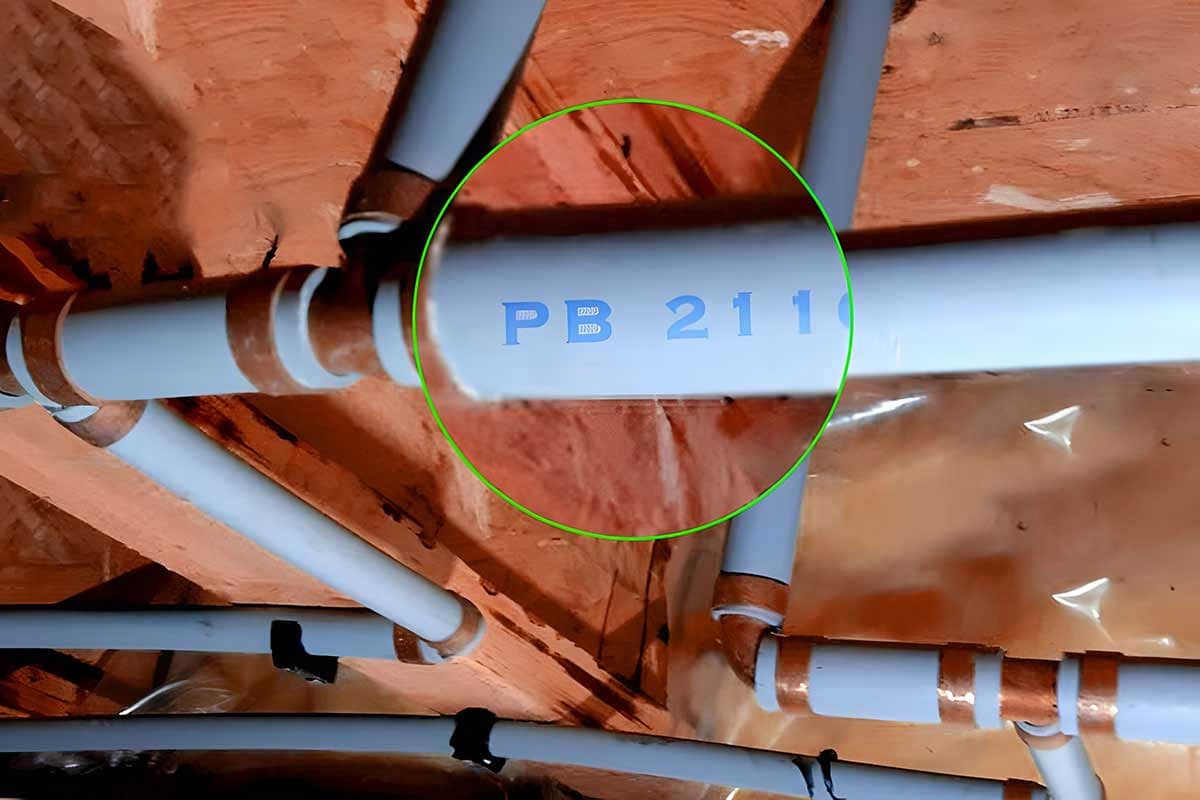 Close-up of Poly B plumbing pipes marked “PB,” illustrating how to identify polybutylene in older BC homes.