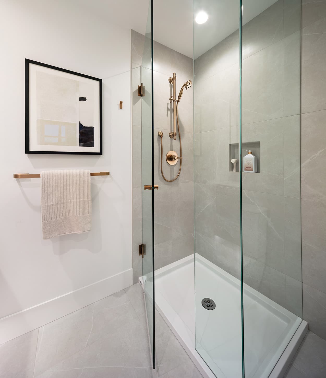 Glass-enclosed shower detail at Smith & Farrow Coquitlam West presale by Boffo Developments, located at 720 Farrow Street, highlighting brushed metal fixtures, integrated shower niche, and large-format tile designed for a spa-inspired bathroom experience.