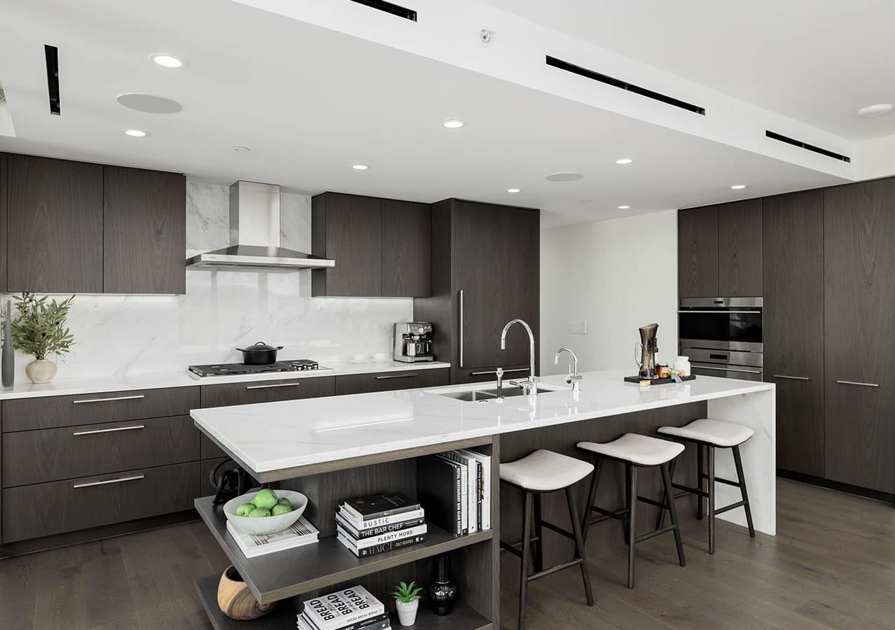 Contemporary kitchen interior at 1535 Howe Vancouver with dark wood cabinetry, large island, integrated Wolf appliances, and marble backsplash in a luxury Downtown Vancouver residence at 1335 Howe Street.