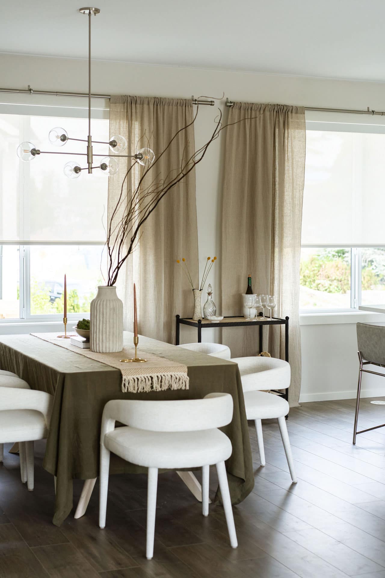 Formal dining area at Fox & Aikins presale townhomes in South Surrey by Park Ridge Homes, located at 1871 165A Street, featuring a rectangular dining table, upholstered chairs, floor-to-ceiling windows with linen curtains, modern chandelier, and warm wood flooring.