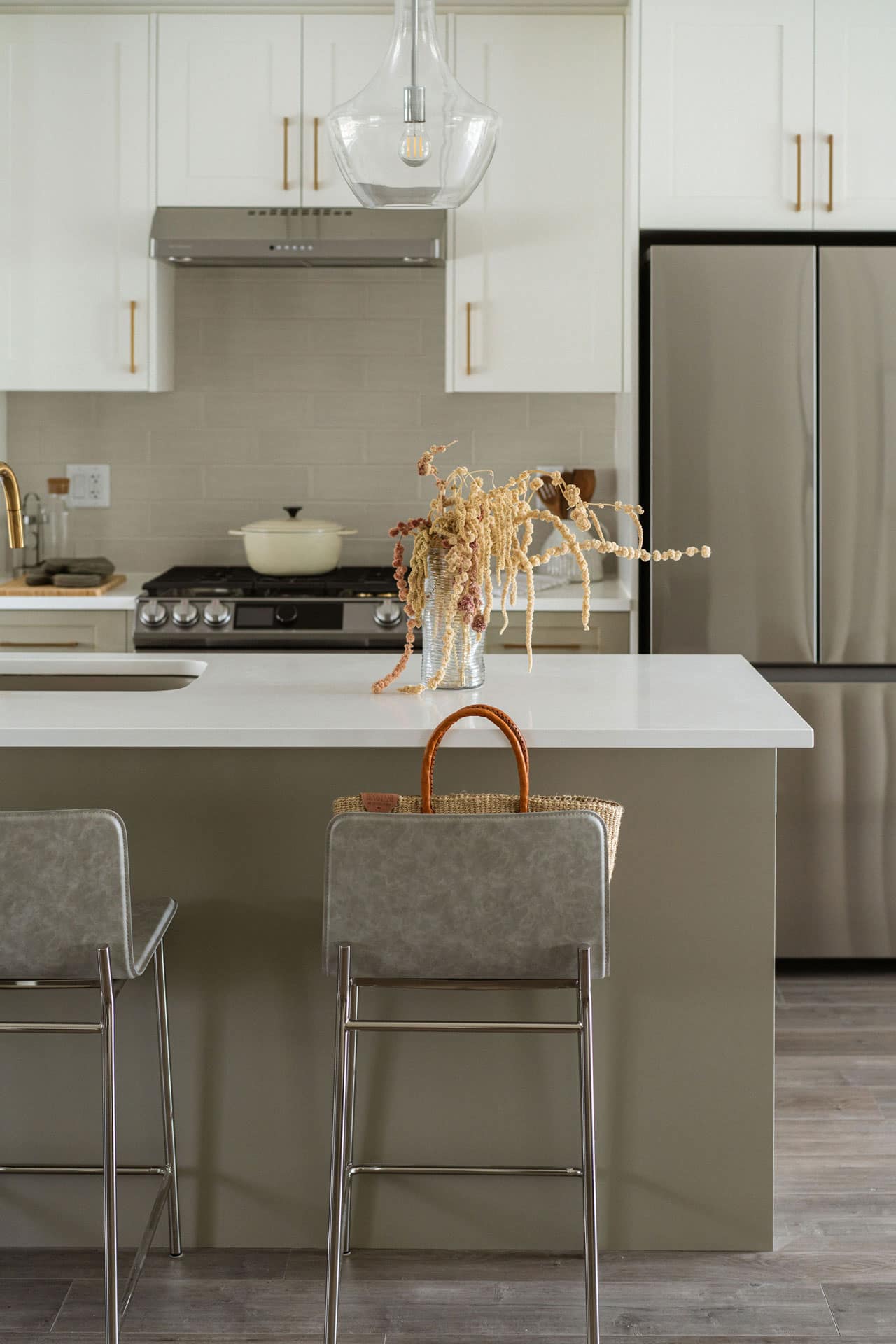 Kitchen island at Fox & Aikins South Surrey by Park Ridge Homes, located at 1871 165A Street, featuring quartz countertops, stainless steel appliances, pendant lighting, white shaker cabinetry, and bar seating in a bright open layout.