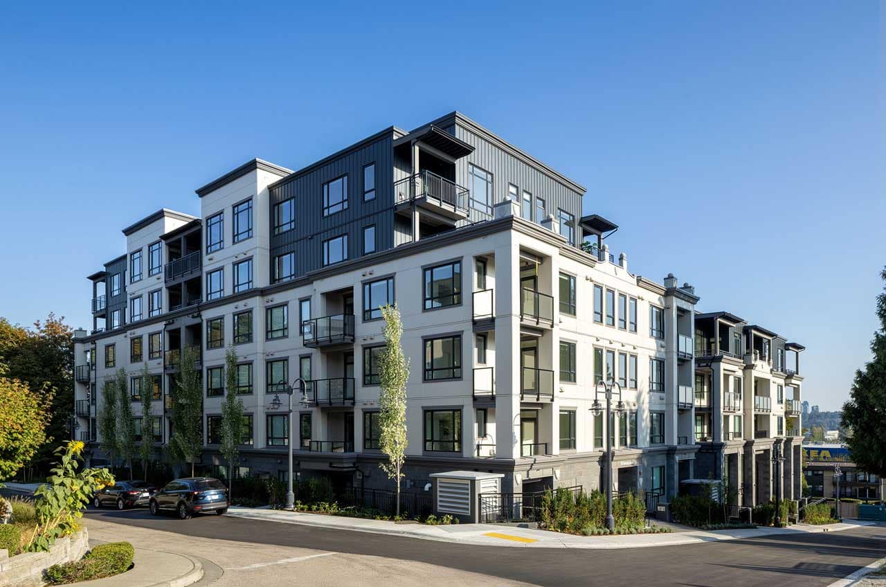 Street-level exterior view of Bastille Coquitlam, a contemporary mid-rise condominium development by Porte Homes at 209 Lebleu Street in Coquitlam's Maillardville neighbourhood, featuring modern architecture, contrasting white and dark façades, private balconies, landscaped streetscapes, and residential surroundings.