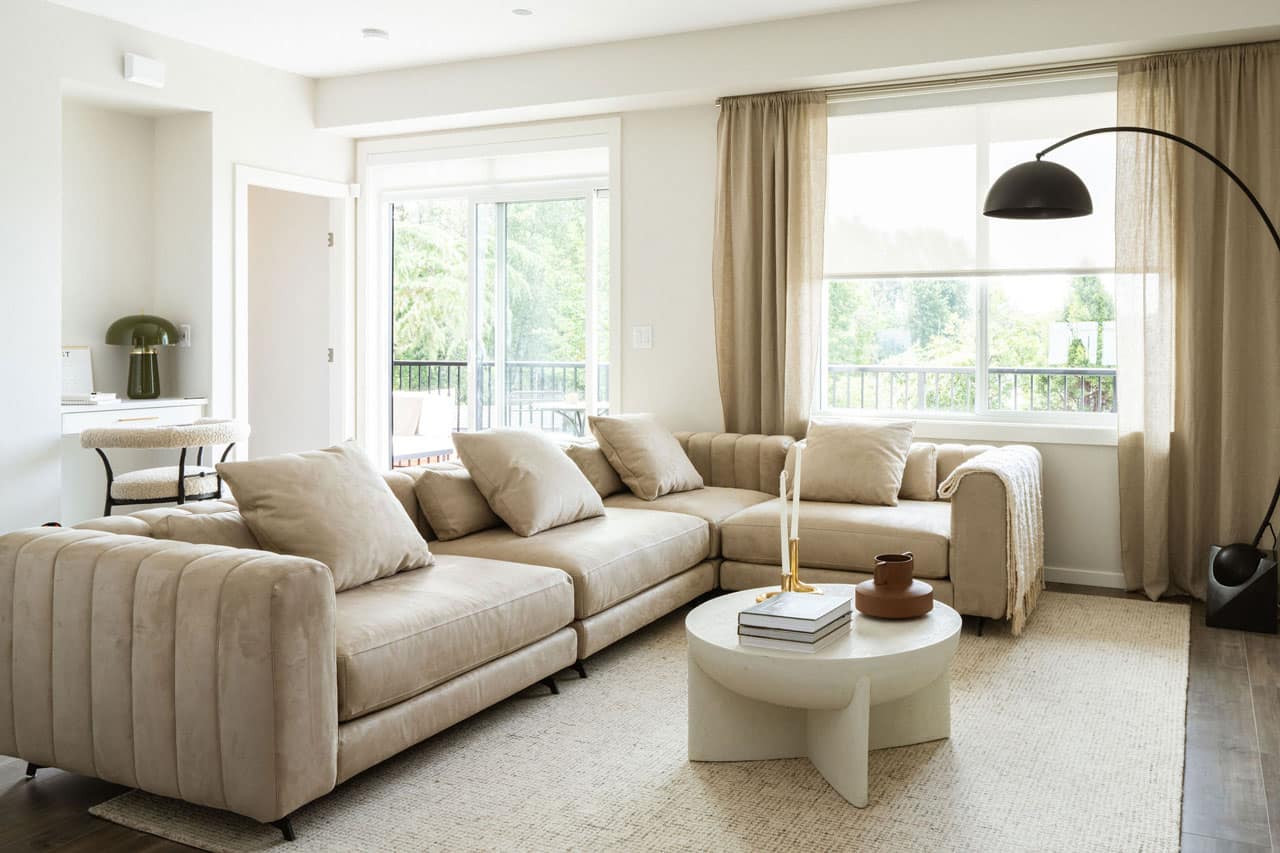 Living room at Fox & Aikins South Surrey townhomes by Park Ridge Homes, located at 1871 165A Street, featuring a large sectional sofa, oversized windows, balcony access, modern coffee table, wide plank flooring, and open-concept layout.