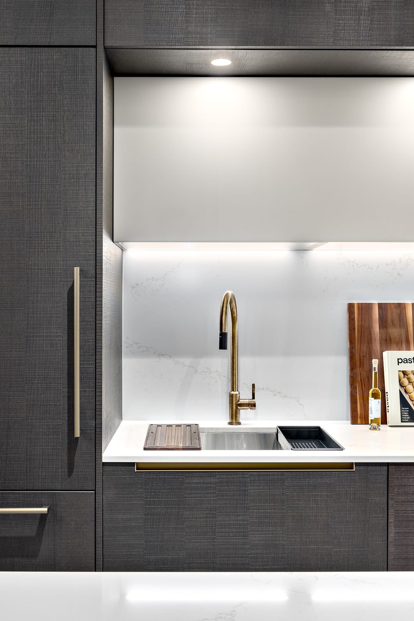 Dark cabinetry kitchen with brass faucet and quartz countertop at Italia by Solterra