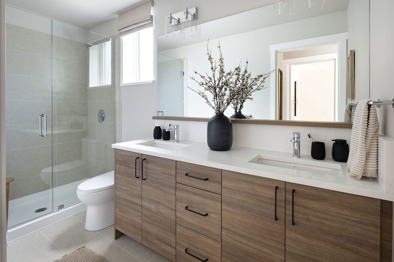 Spa-inspired ensuite bathroom at Rindall Port Coquitlam with double-sink vanity, quartz countertops, woodgrain cabinetry, and a frameless glass shower by Woodbridge Homes.