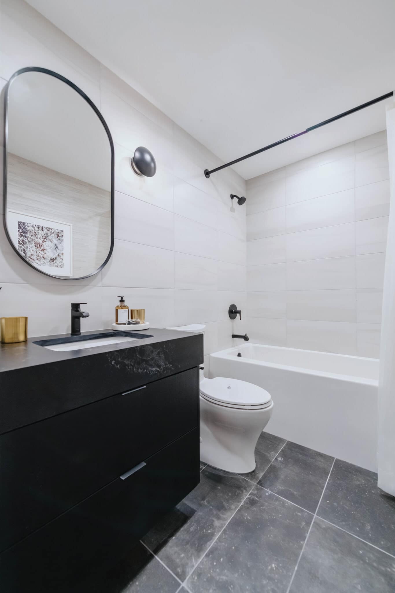 Modern bathroom at Reign Metrotown with black vanity, matte fixtures, and tiled walls.