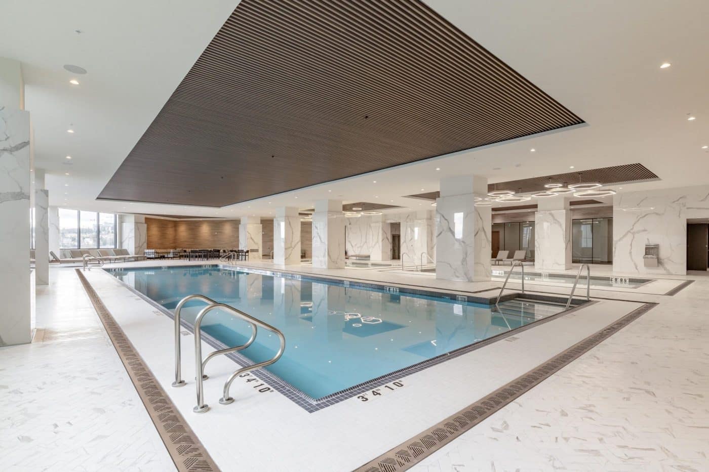 Luxurious indoor swimming pool and spa facility at Pine & Glen Coquitlam by Onni Group, featuring marble-inspired finishes, hot tub, lounge seating, and wellness amenities at 1175 Pinetree Way.