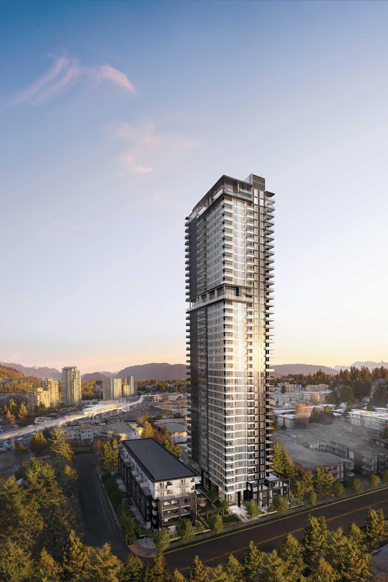 Exterior view of Jinju Coquitlam by Anthem Properties in Burquitlam at 533 Cottonwood Avenue, featuring a modern high-rise tower at sunset with surrounding cityscape, SkyTrain corridor, and mountain backdrop.