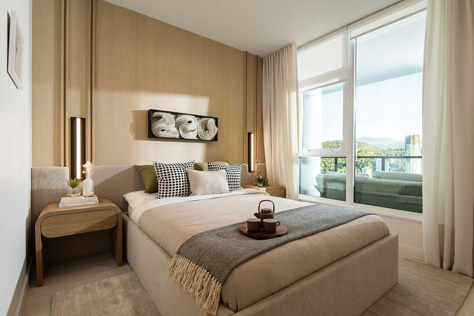 Bedroom interior at Jinju Coquitlam presale development by Anthem Properties, 533 Cottonwood Avenue in Burquitlam, showcasing warm wood paneling, soft textiles, large window, and natural light with city and mountain outlook.