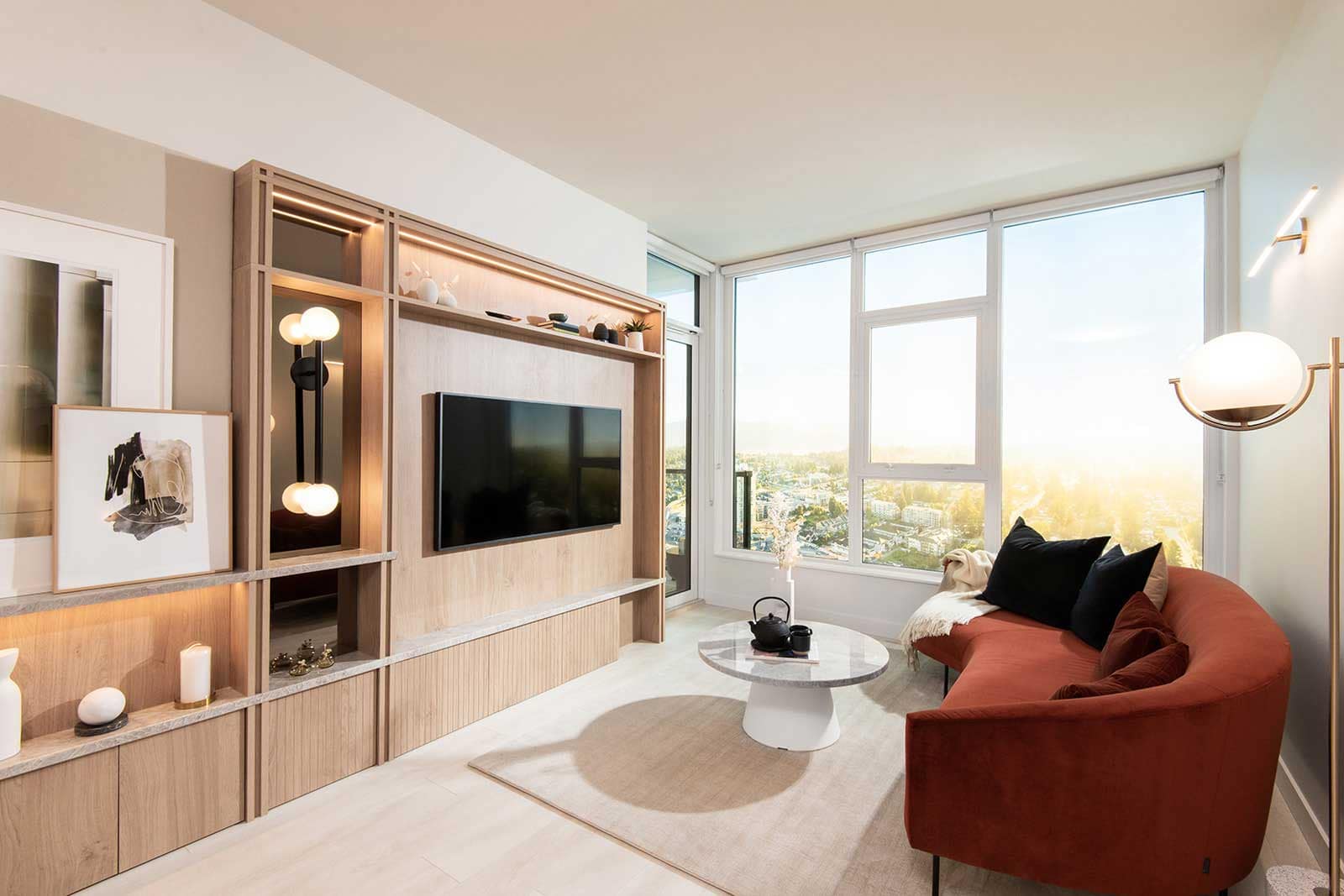 Living room at Jinju Coquitlam presale condos by Anthem Properties, located at 533 Cottonwood Avenue in Burquitlam, featuring custom millwork, built-in shelving, modern lighting, and large windows with expansive city and sunset views.