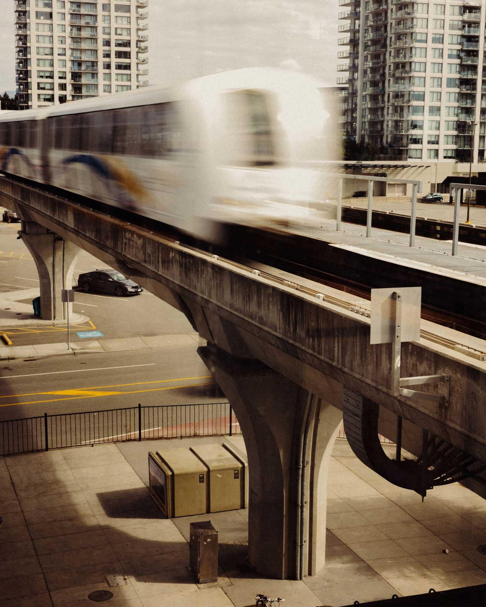 SkyTrain passing through Burquitlam near Olo Coquitlam by Rize at 616 Kemsley Avenue, showing rapid transit access with nearby residential towers and urban infrastructure.