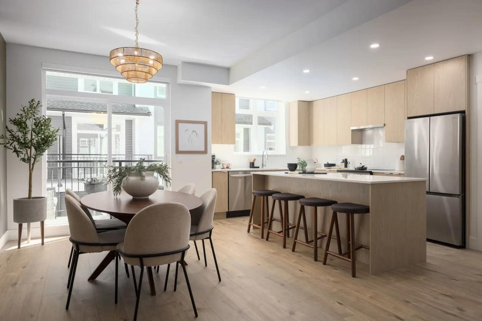 Open-concept kitchen and dining area inside Chelsea at The Boroughs presale townhomes in Surreyโs Sunnyside Heights neighbourhood by Northwest Development at 16325 21 Avenue, featuring a large kitchen island with bar seating, stainless steel appliances, modern cabinetry, and dining space overlooking the balcony.