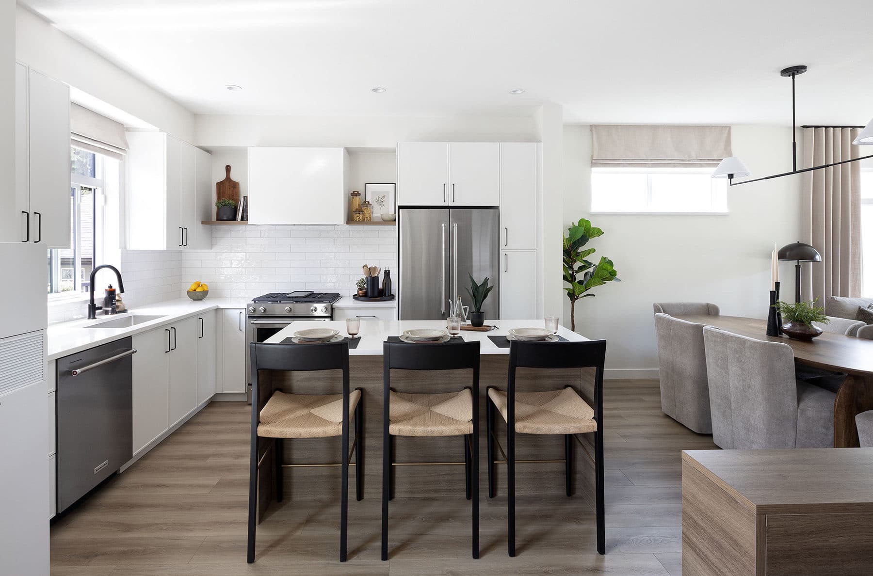 Modern open-concept kitchen at Rindall Port Coquitlam featuring a large quartz island, white shaker cabinetry, premium stainless steel appliances, and wide-plank flooring in a Woodbridge townhome at 2150 Rindall Avenue in Central Port Coquitlam.