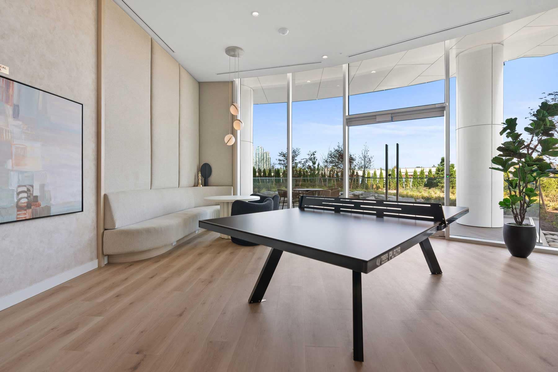 Games room at Icon at Southgate City Burnaby featuring table tennis, lounge seating, and floor-to-ceiling windows overlooking outdoor amenities.