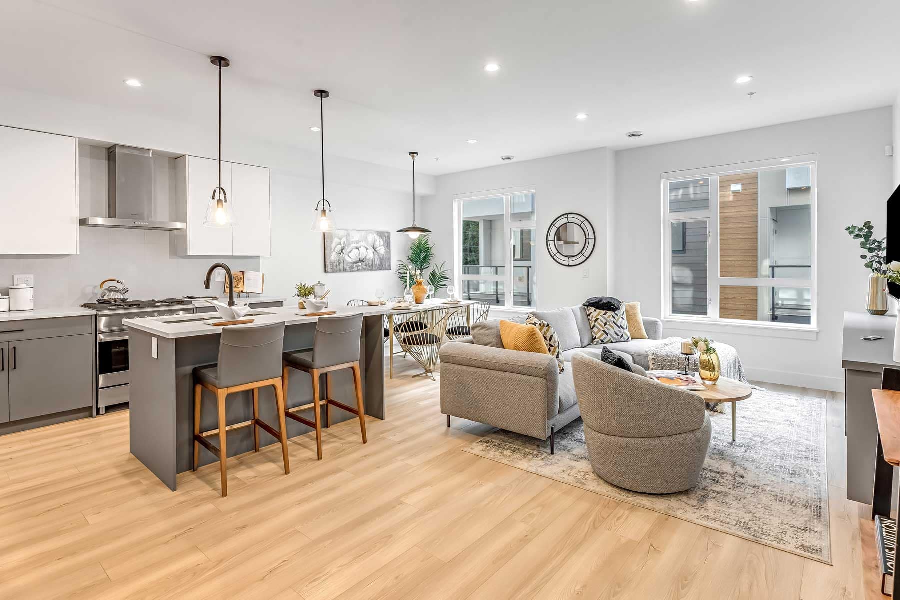 Bright contemporary living and dining area inside Park Avenue Langley townhomes by Apcon Group featuring modern kitchen island, large windows, and open-concept design at 7946 204 Street.