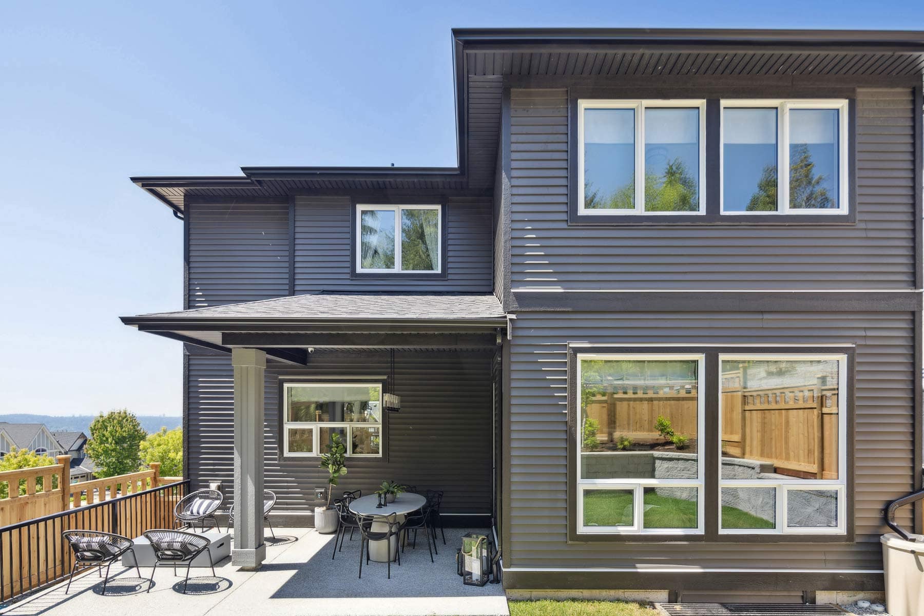 Private backyard patio at Timber's Edge Burke Mountain in Coquitlam by Foxridge Homes, with covered seating area, outdoor dining space, and fenced yard backing onto greenery