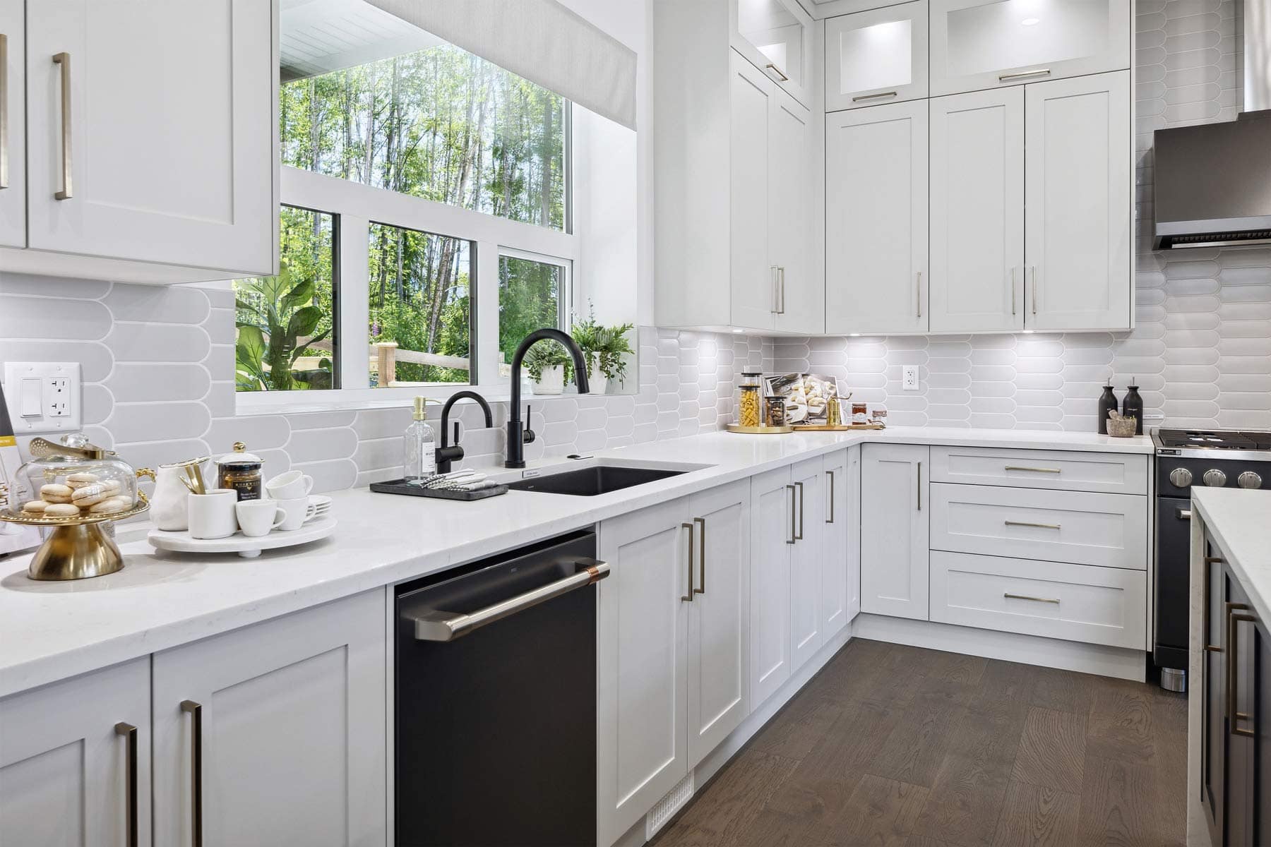 Bright modern kitchen at Timber's Edge Burke Mountain in Coquitlam by Foxridge Homes featuring white cabinetry, quartz countertops, large windows, and stainless steel appliances