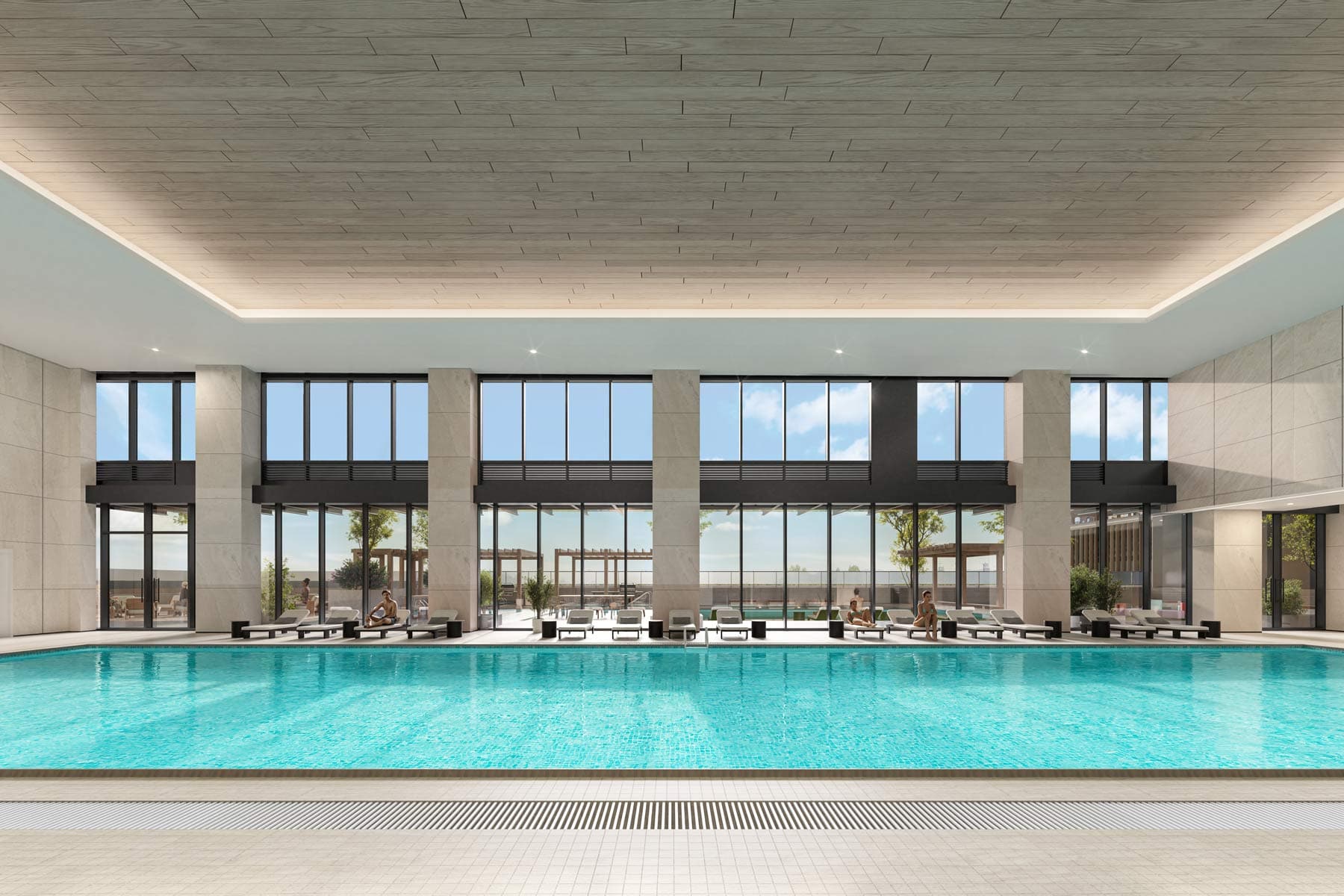 Large indoor swimming pool at West 57th Vancouver by Onni Group at 500 West 57th Avenue in Vancouverโs Cambie neighbourhood, featuring lounge chairs, tall ceilings, and a bright resort-style setting